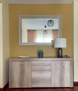 a wooden dresser with a mirror and a lamp on it at El apartamento de Adriana en Torrelavega. in Torrelavega