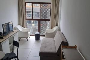 un soggiorno con divano, sedie e finestra di Edificio Nau no coração da Barra a Salvador
