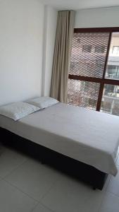 a bed in a room with a window at Edificio Nau no coração da Barra in Salvador