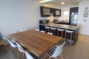 a kitchen with a wooden table and white chairs at frente al mar 21d in Tonsupa