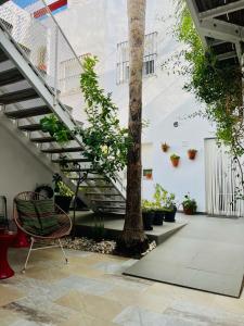 a room with stairs and a chair next to a tree at Chipibeach, Hostal Boutique in Chipiona