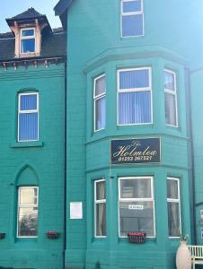 een groen gebouw met een bord ervoor bij The Holmlea in Blackpool