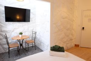 a room with a table and chairs and a tv on a wall at Auberge Mélilot in Dolbeau