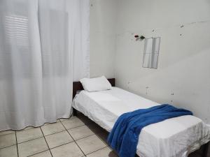 Habitación pequeña con cama con manta azul. en Mini Hostel, en Tutóia