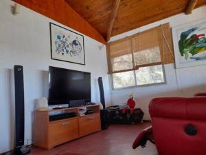 - un salon avec une télévision et un canapé rouge dans l'établissement Agradable Casa a Orillas del Lago Rapel, à Las Cabras