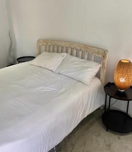 a bed with white sheets and a lamp on two tables at Villa Manuia Guest Room in Koh Samui 