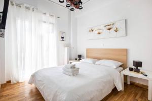biała sypialnia z białym łóżkiem i oknem w obiekcie A modern apartment in the heart of Athens w Atenach