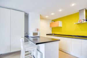 una cocina con armarios blancos y una pared amarilla en Le Studio 44, en Han-sur-Lesse