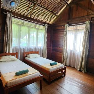 a bedroom with two beds and a window with curtains at UKCC (Ujung Karang Conference Center) in Sabong