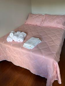 a bed with pink sheets and towels on it at Apartamento Centro ao lado do Country Club in Nova Friburgo