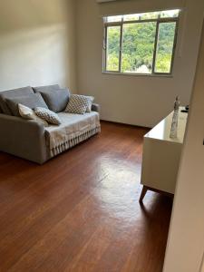 a living room with a couch and a wooden floor at Apartamento Centro ao lado do Country Club in Nova Friburgo