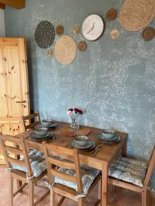 a wooden table with chairs and a clock on the wall at Alma Apartmanház in Harkány