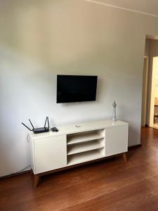 a white entertainment center with a television on a white wall at Apartamento Centro ao lado do Country Club in Nova Friburgo