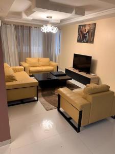 a living room with a couch and a tv and chairs at Good Time Guaranteed •7 in Dakar
