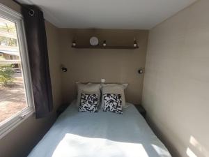 uma pequena cama num pequeno quarto com almofadas em Mobil-home, 3 ch , 6 personnes em Le Pont Legé
