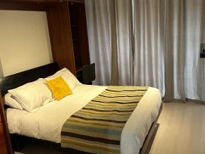 1 dormitorio con 1 cama con almohada amarilla en Apart hotel Fraga, en Santiago