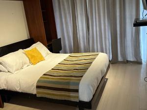 a bedroom with a bed with a yellow blanket on it at Apart hotel Fraga in Santiago