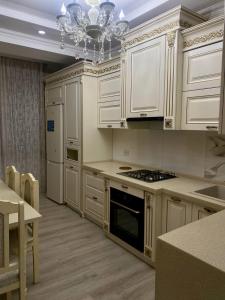 a kitchen with white cabinets and a table and a chandelier at 4х комнатная квартира in Bishkek