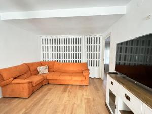 a living room with an orange couch and a flat screen tv at Piso Albatros en el centro in Platja d'Aro