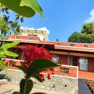 a building with a red roof and red flowers at The Ixora - A Boutique Homestay in Varkala