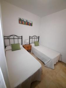 2 Betten in einem Zimmer mit weißen Wänden in der Unterkunft Amplio apartamento céntrico in Peñíscola