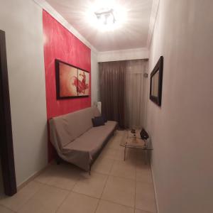 a living room with a couch and a red wall at Vaggoula's Luxury Apartment 1 in Serres