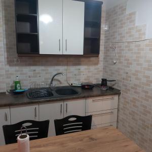 a kitchen with white cabinets and a sink and a table at Vaggoula's Luxury Apartment 1 in Serres