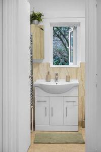 baño con lavabo blanco y ventana en Modern 2 Bedroom Townhouse Flat in King’s Cross, en Londres