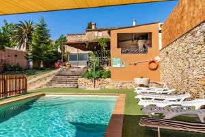 a swimming pool with chairs and a house at Can Nentia in Fonteta