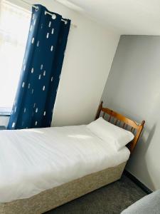 1 dormitorio con 1 cama con cortina azul en BG Homes, en Peterborough