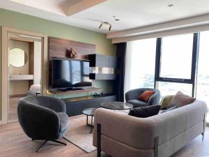 ein Wohnzimmer mit einem Sofa, Stühlen und einem TV in der Unterkunft Modern 2BD Panoramic view downtown in Istanbul