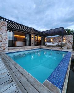 a large swimming pool with a wooden deck and a house at Lira Boutique Lodge in Thohoyandou
