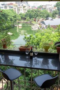 balcón con 2 copas de vino y vistas al río en POMELO - Sun's Homestay - Lake View, en Hanói