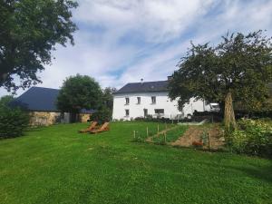 ein weißes Haus mit zwei Bänken im Hof in der Unterkunft Gîte dans ancien corps de ferme à 5mn de Pompadour in Troche