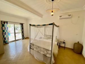a bedroom with a bed with a canopy at KEUR MATY Charmante et Moderne Villa 5 chambres, 5 salles de bains à Warang in Ouoran +38 photos