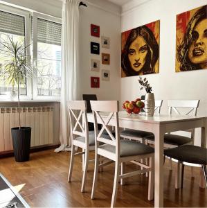 a dining room with a white table and chairs at Bloom apartments in Belgrade