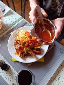 a person holding a pot of gravy over a plate of food at LE PETIT VERMONDOIS in Le Bacon