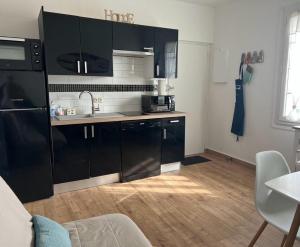 a kitchen with black cabinets and a wooden floor at Appartement proche plage et commerces in Royan