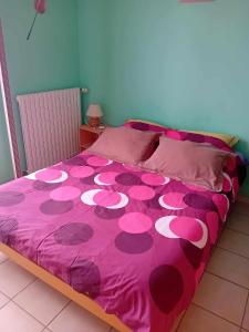 een bed met een roze sprei met roze bloemen erop bij LE PETIT VERMONDOIS in Le Bacon