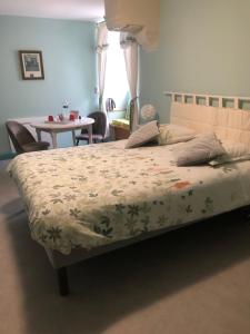 1 dormitorio con 1 cama y 1 mesa con sillas en Les chambres du Moulin, en Les Epsailles