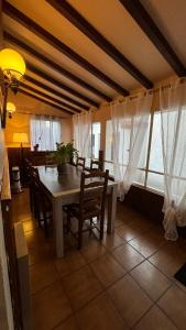 uma sala de jantar com mesa, cadeiras e janelas em Location appartement dans Maison Basque em Urcuit
