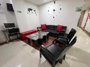 a living room with a couch and a table and a clock at Hotel Dorado Gold in Bogotá