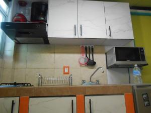 cocina con armarios blancos, fregadero y microondas en Lofts San Ángel, en Ciudad de México