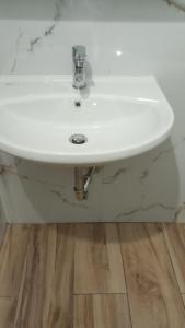 lavabo blanco en un baño con suelo de madera en Primavera Apartments, en Sarandë