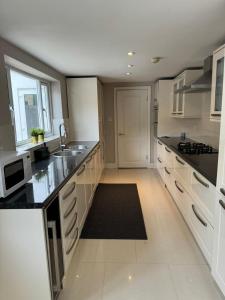 a large kitchen with white cabinets and black counter tops at Brentford Guest Rooms in Brentford