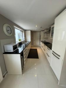 a large white kitchen with a clock on the wall at Brentford Guest Rooms in Brentford