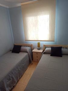 two beds in a bedroom with a window and a table at Apartamento en Magic World. Nueva Marina Dor in Oropesa del Mar