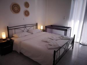 1 dormitorio con 1 cama blanca grande y toallas. en Nord Guesthouse, en Néos Pírgos