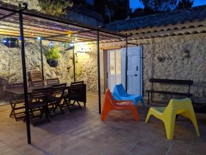 a patio with colorful chairs and a table and a building at La maison de Daniel - Esparron-de-Verdon in Esparron-de-Verdon