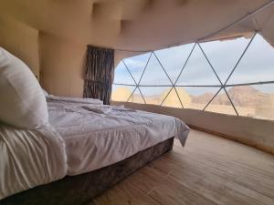 ein Schlafzimmer mit einem Bett und einem großen Fenster in der Unterkunft WADl RUM DESERT CAMP in Wadi Rum